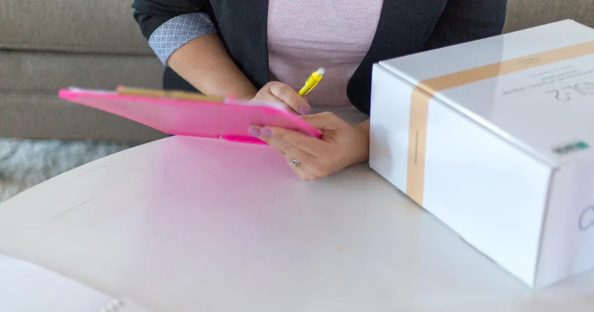 A person ticking a checklist on a tablet next to a parcel
