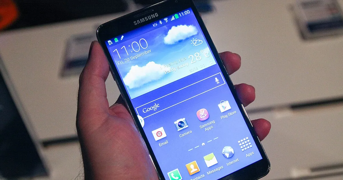 A hand holding a smartphone showing its home screen of app icons