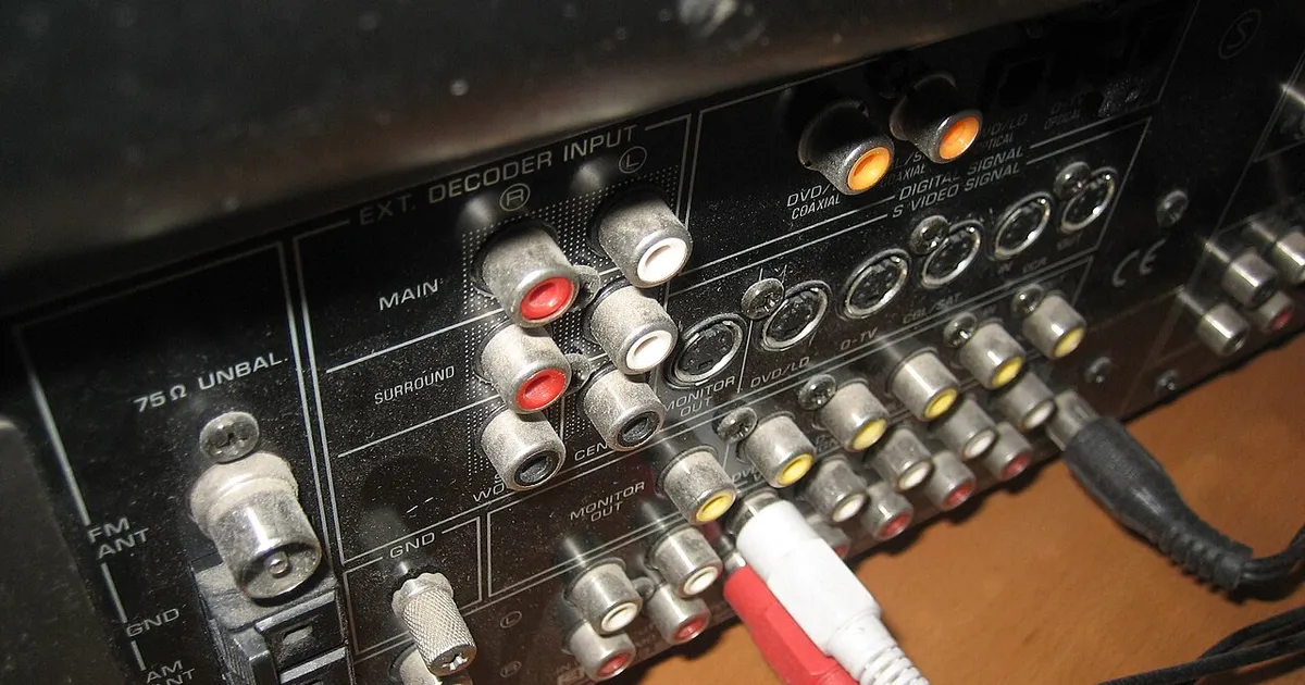 The back panel of an AV receiver with many cables plugged into standard connectors